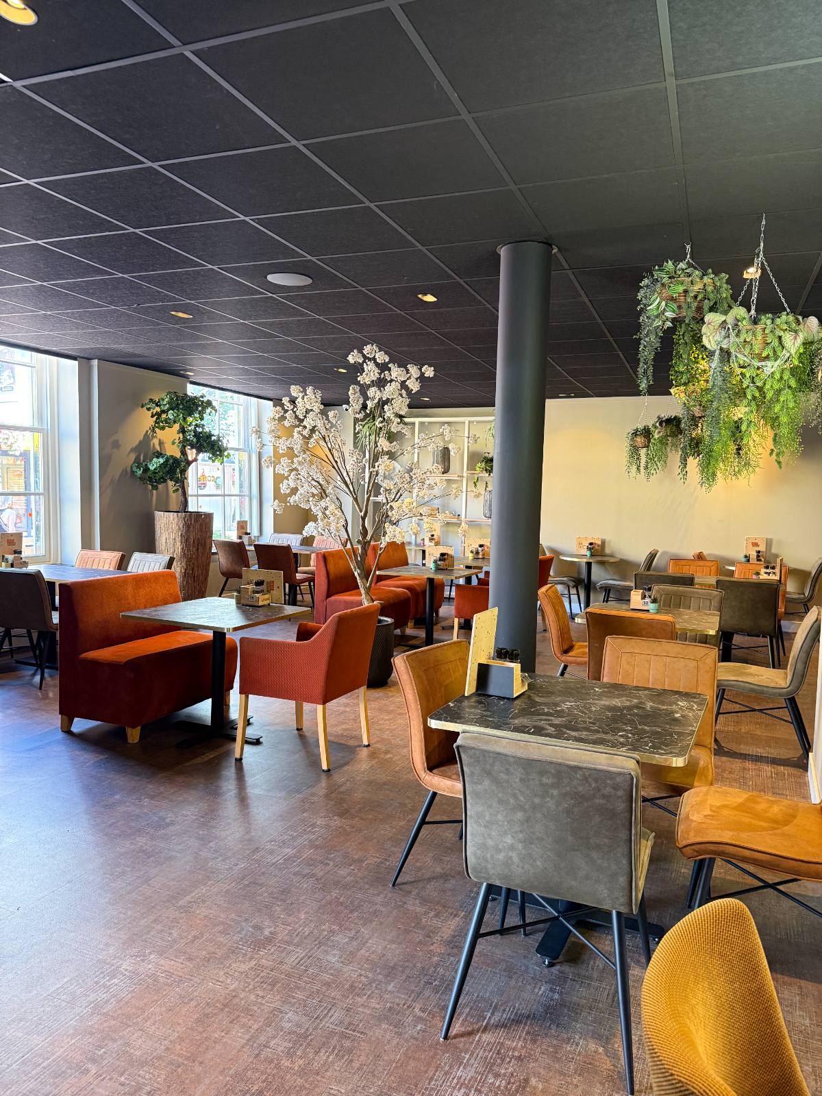 Interieur van Knus & Cosy met bloesemboom, hangplanten en zitplekken.